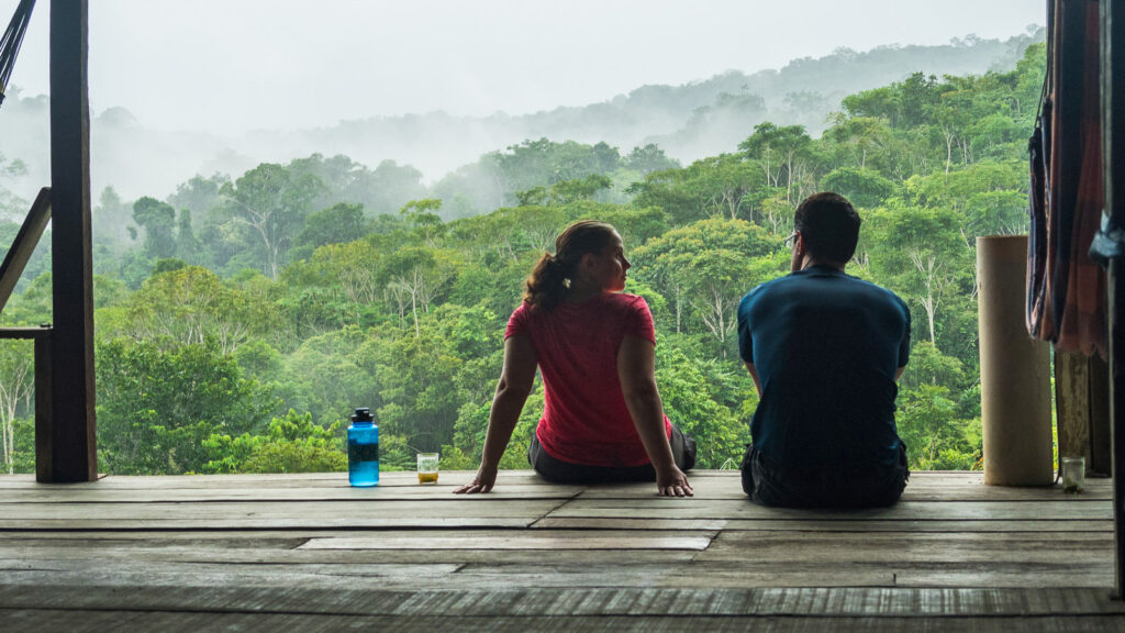 Pärchen sitzt auf der Holzveranda mit Blick auf den Amazonas-Regenwald