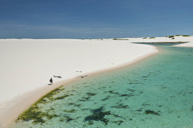 Spaziergänger auf dem weißen Sand entland des Wassers im Maranhenses Nationalpark