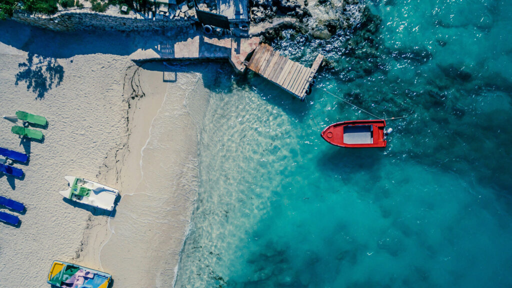 Tretboote am Strand und türkises Meer von oben