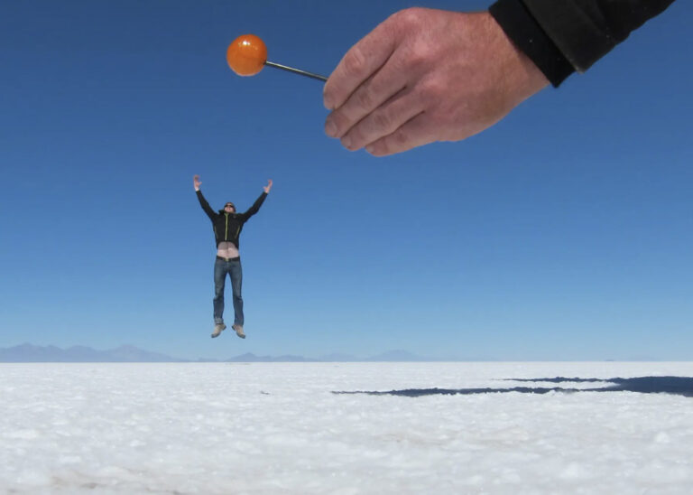 Mann springt scheinbar zum Lolli in der Salar de Uyuni