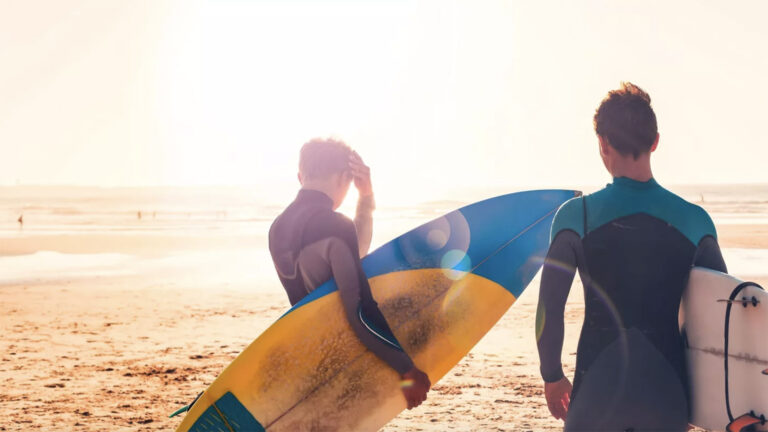 Surfer im Gegenlicht auf dem Weg zum Meer