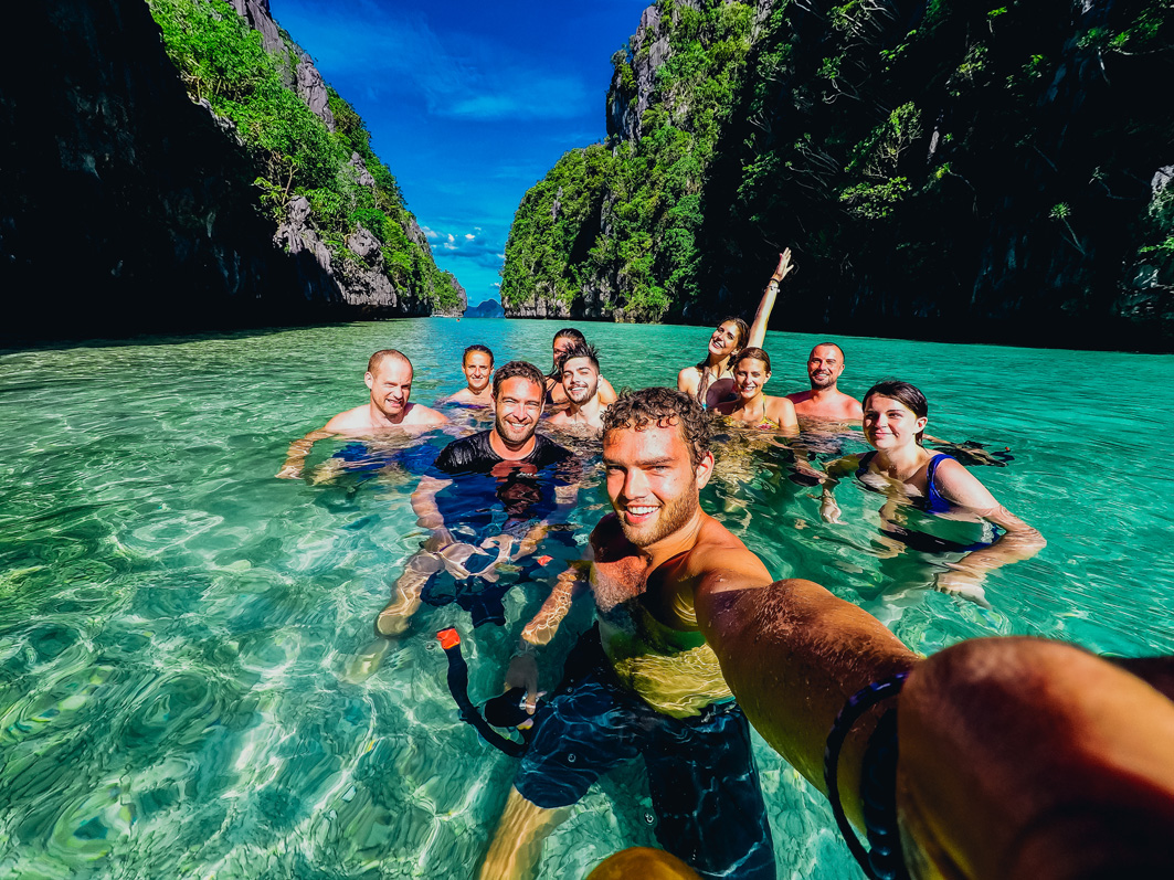 Junge Backpacker Gruppe auf einer TruTravels Gruppenreise im türkisblauen Meer der Philippienen