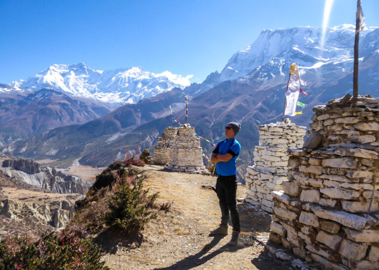 Reisender posiert vor Steinhaufen und Gebetsfahnen im Himalaya