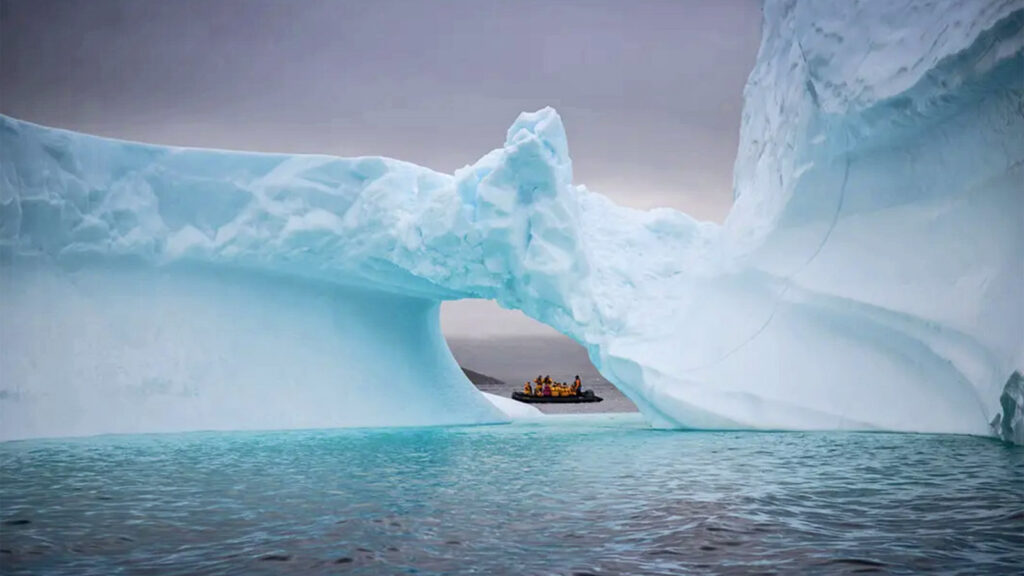Gruppe im Zodiac hinter Eisberg