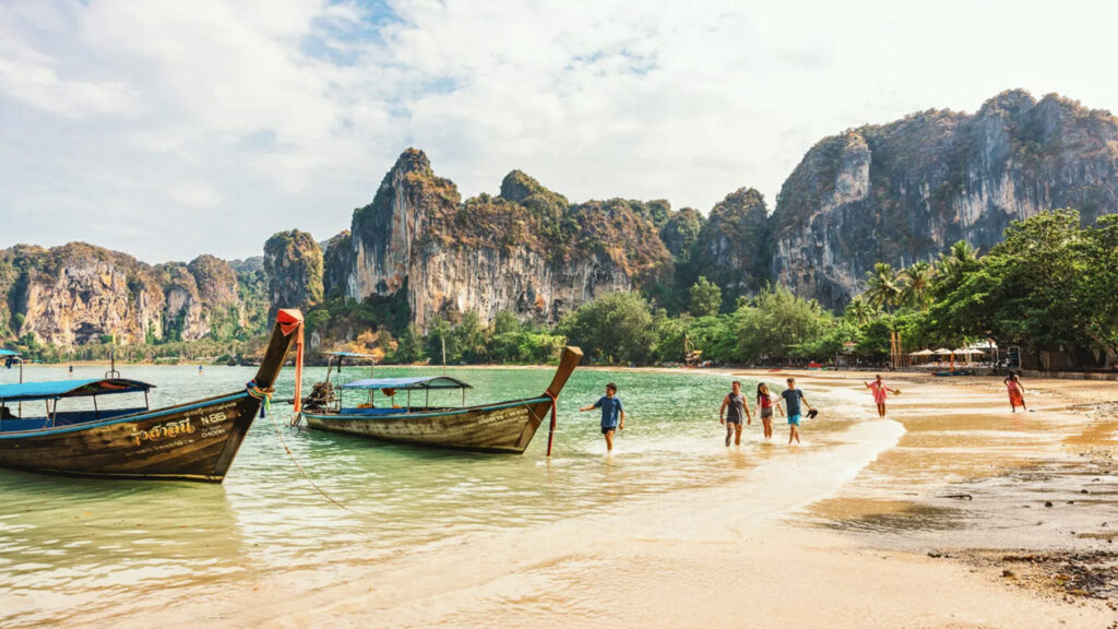 Junge Leute am Strand in Thailand und Langheckboot