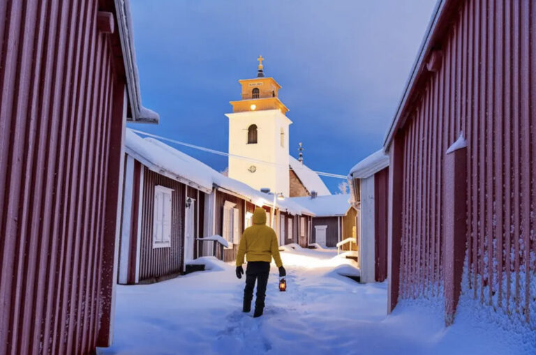 Mann läuft mit Laterne duch den Schnee auf die Nederlua-Kirche zu