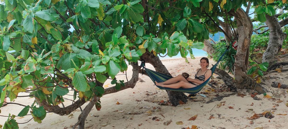 Reisende mit Kokosnuss in Hängematte am Strand