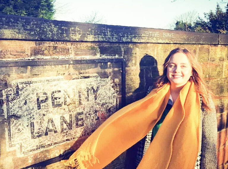 Reisende posiert vor Penny-Lane-Schild in Liverpool