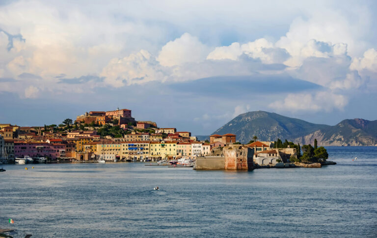 Blick vom Meer aus auf die bunten Häuser von Portoferraio und grüne Hügel
