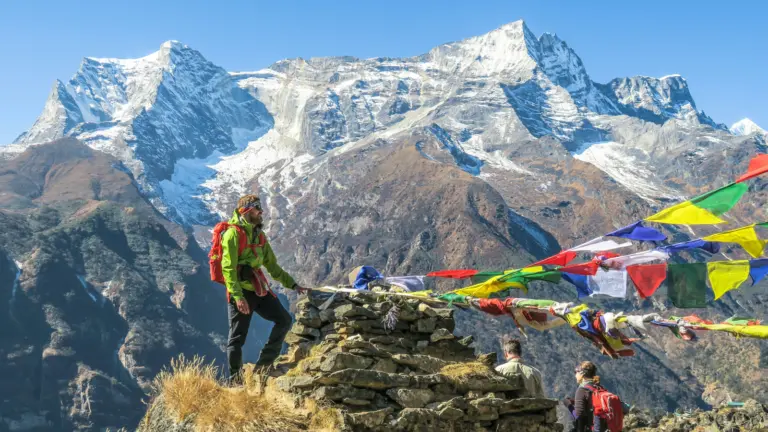 Nepal Trekking Gruppe auf Bergwanderung im Himalaya mit buddhistischen Gebetsfahnen und verschneiten Gipfeln im Hintergrund