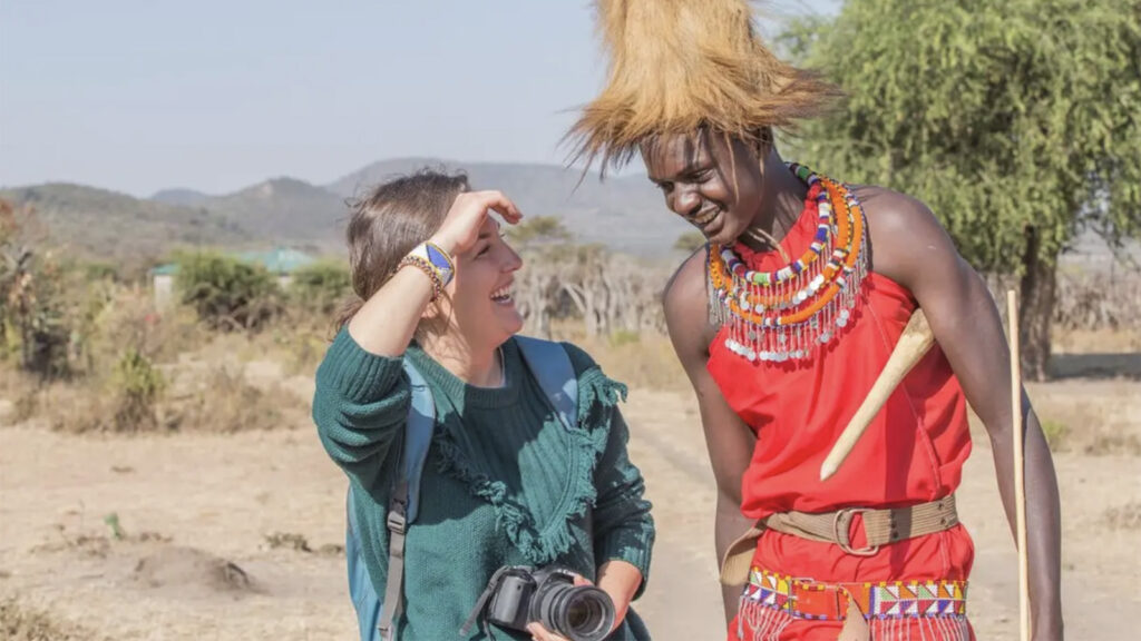 Reisende mit Fototapparat im Gespräch mit einem Massai