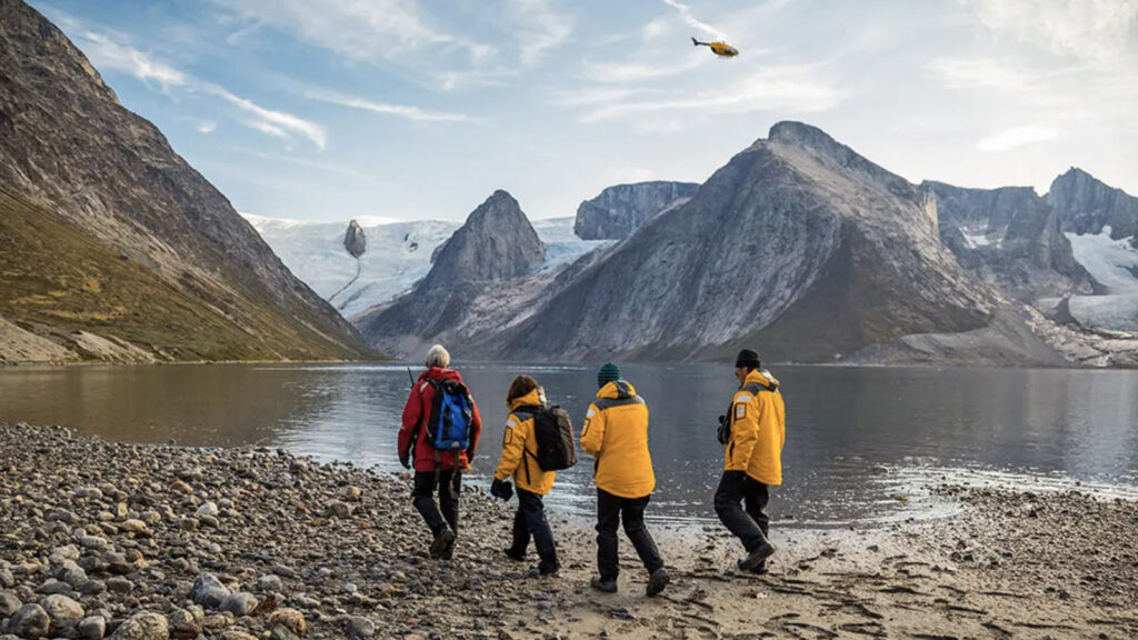 Expeditionsgruppe im grönländischen Fjord, Helikopter am Himmel