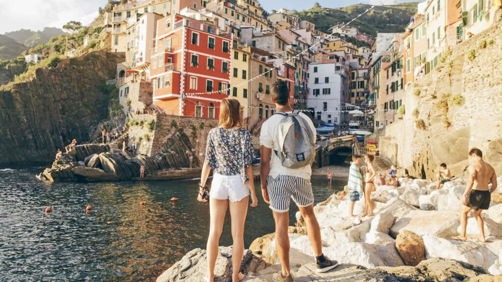Zwei junge Leute (von hinten) blicken auf die bunten Häuser von Cinque Terre