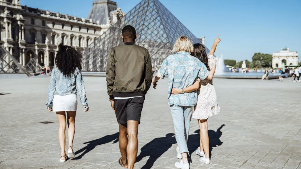 Junge Leute (von hinten) laufen über den Platz vor dem Louvre