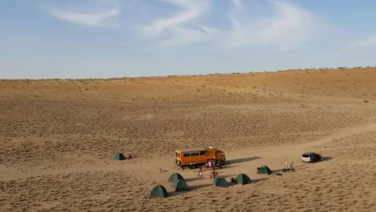 Overland-Truck und Zelte in der Karakum-Wüste in Turkmenistan während einer Abenteuerreise durch Zentralasien