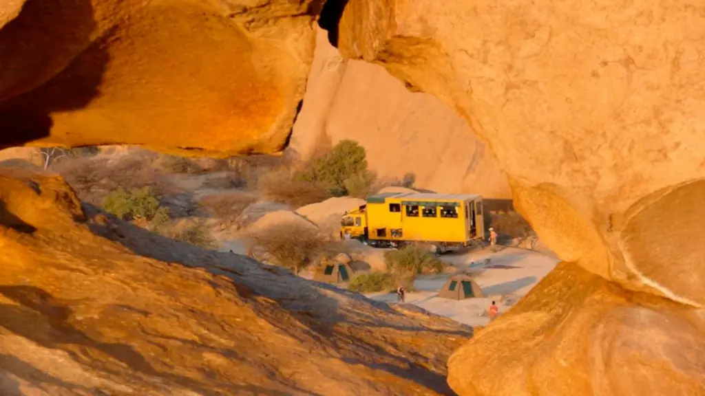 Overland Truck und Zelte zwischen roten Felsen in der Wüste Namibias