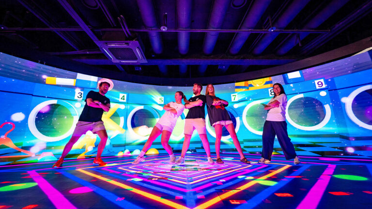 Junge Leute machen K-Pop Tanzschritte vor Neon-Lichter-Hintergrund