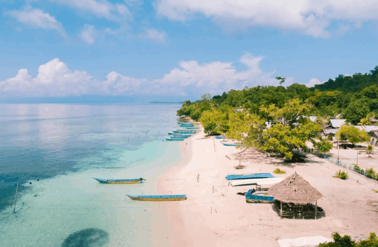 Weißer Sandstrand mit traditionellen Fischerbooten in Raja Ampat, Indonesien – paradiesische Kulisse für den Raja Ampat Urlaub