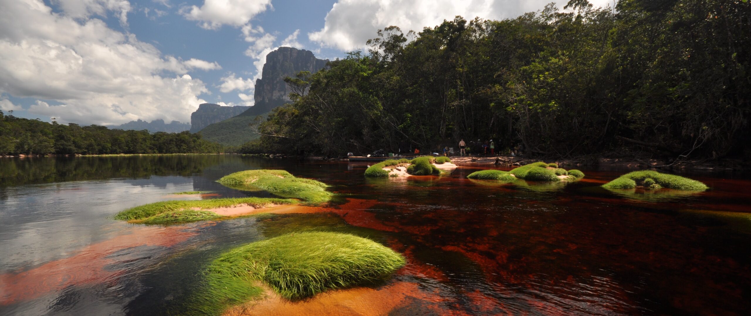 Expedition in der Wildnis Venezuelas mit rotem Fluss, üppigem Dschungel und mächtigem Tepui Massiv im Hintergrund