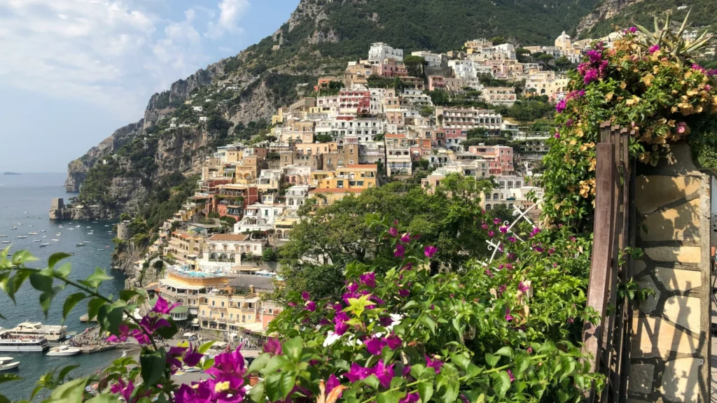 Blick auf Positano an der Amalfiküste mit bunten Häusern, Bougainvillea-Blüten und dem tiefblauen Meer – National Geographic Reisen Süditalien