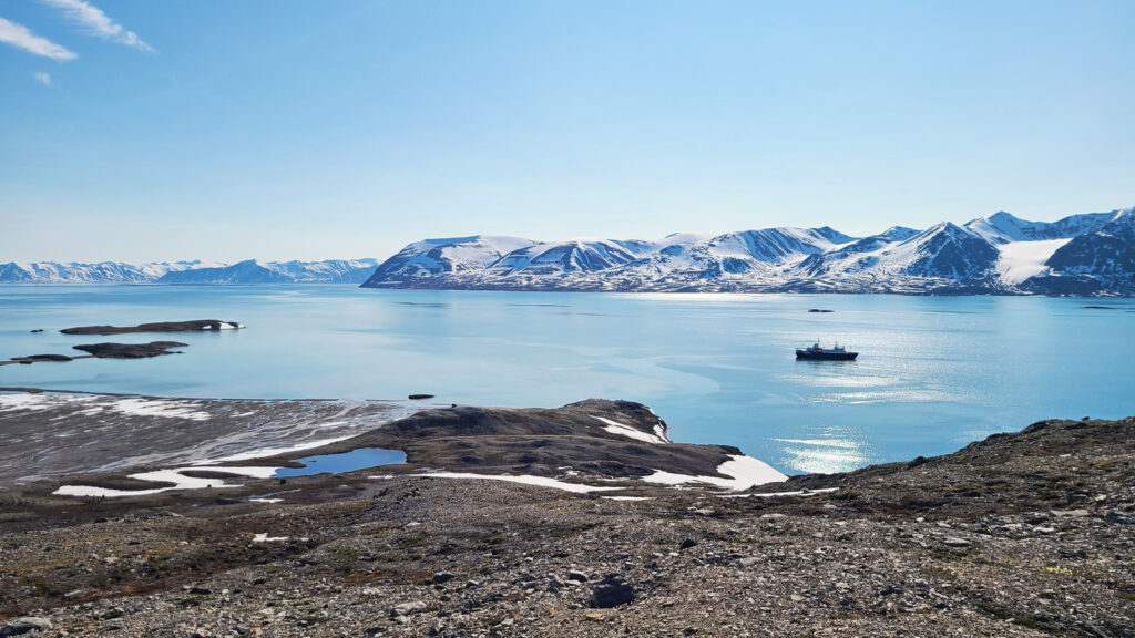 Landschaft in Spitsbergen mit Expeditionsschiff in der Ferne