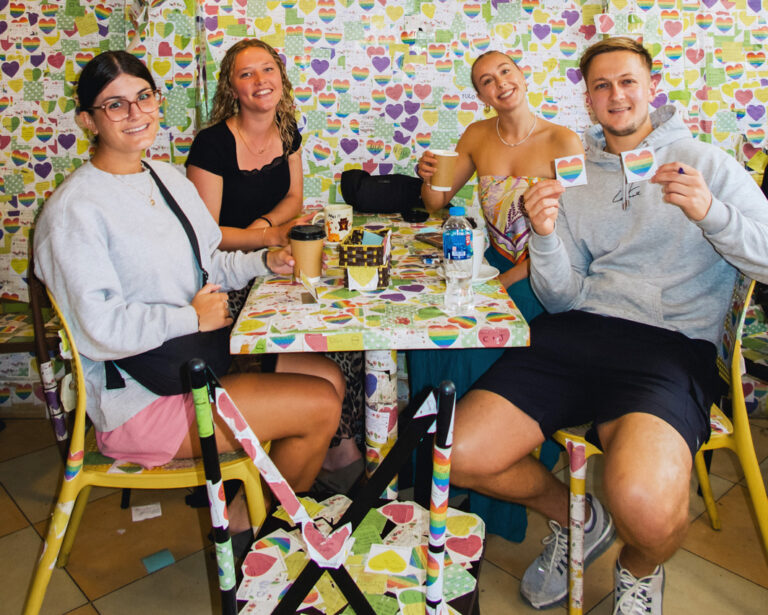 4 Reisende in einem Café mit bunt beklebten Wänden und Tischen