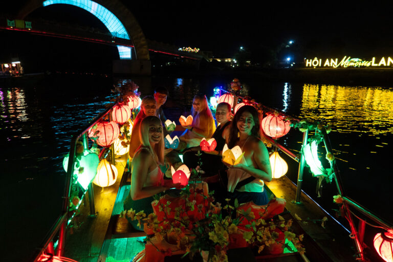 Gruppe im Dunklen mit Laternen auf einem Boot in Hoi An