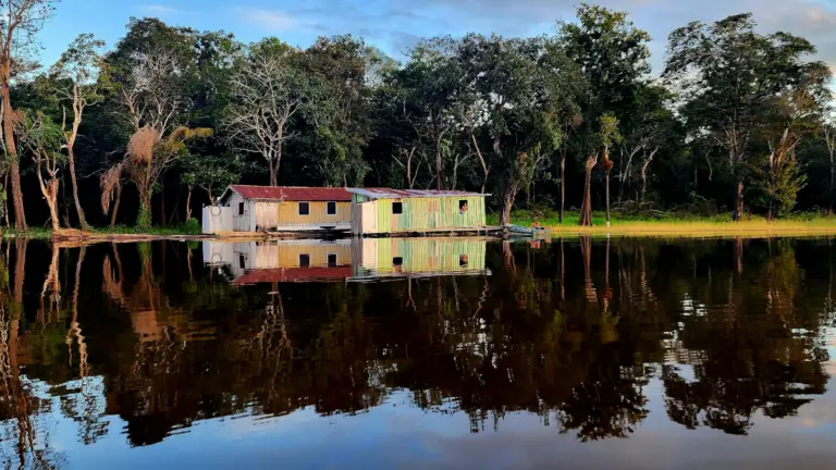Amazonas Flusslandschaft im peruanischen Regenwald mit traditionellen Häusern am Ufer während einer Amazonas Flusskreuzfahrt