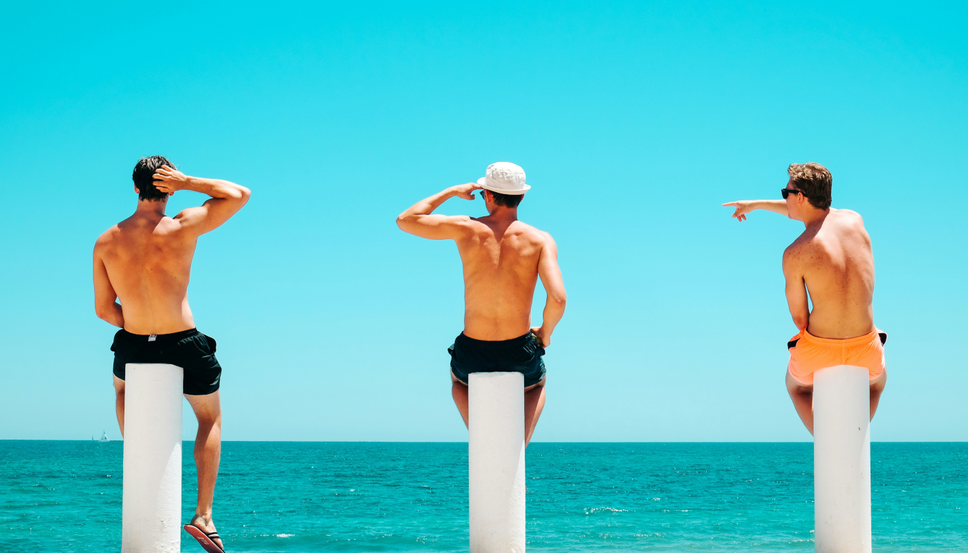 Junge Erwachsene sitzen am Meer und überlegen gemeinsam ihre nächste Reise als Beispiel für Gruppenreisen junge Leute und junge Erwachsene Reisen weltweit