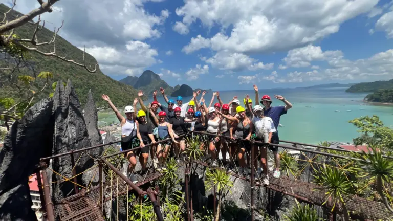 Junge internationale Reisende auf einer Gruppenreise beim Canopy Walk über den Klippen von El Nido auf Palawan mit Blick auf das Meer