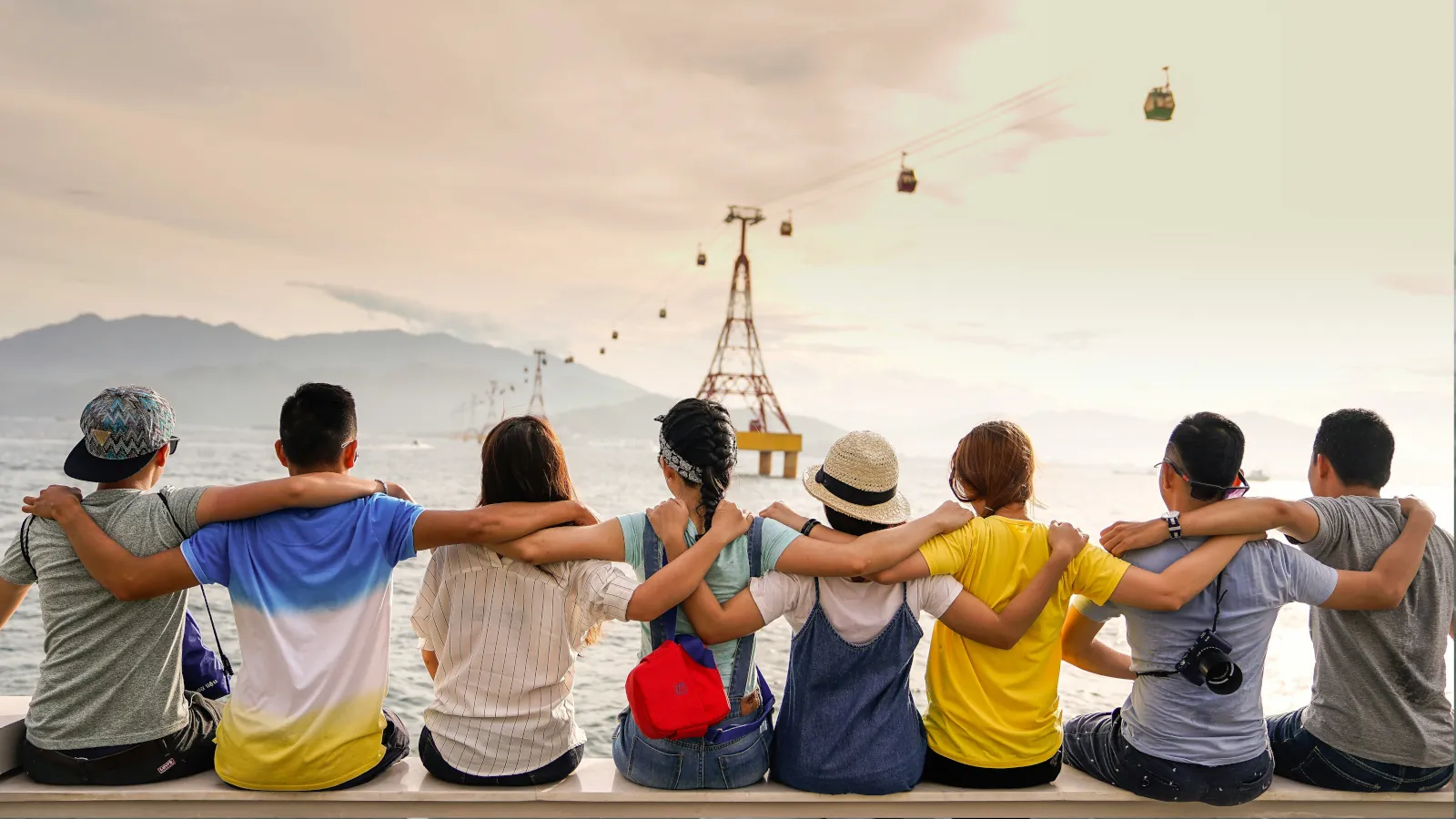 Junge Reisende sitzen gemeinsam am Wasser und erleben auf einer internationalen Gruppenreise neue Freundschaften und Abenteuer