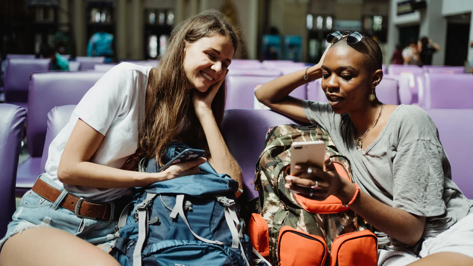 Zwei junge Backpackerinnen planen ihre Reise mit Apps und lernen unterwegs neue Leute kennen
