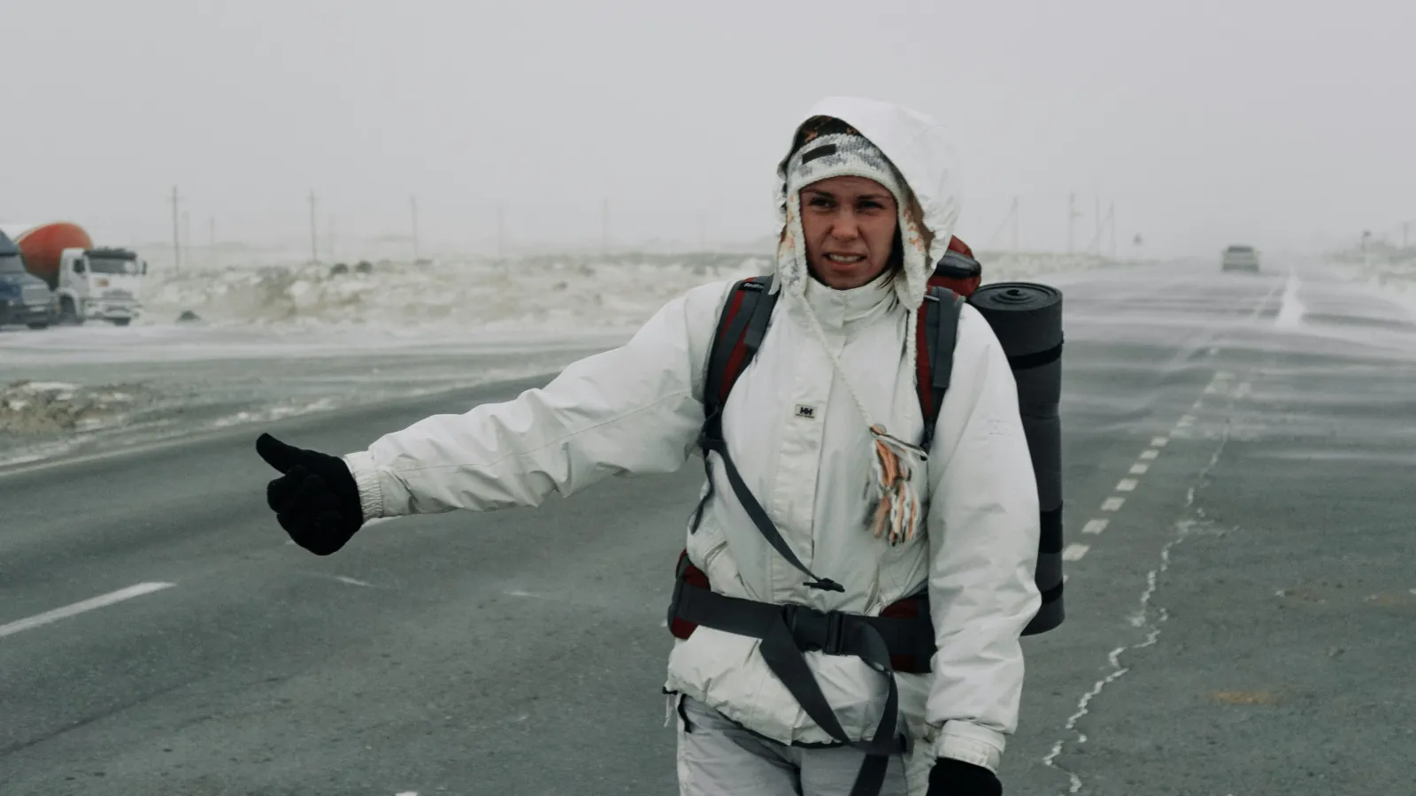 Alleinreisende Backpackerin steht mit Rucksack an einer einsamen Straße und erlebt die Herausforderungen von Solo Travel