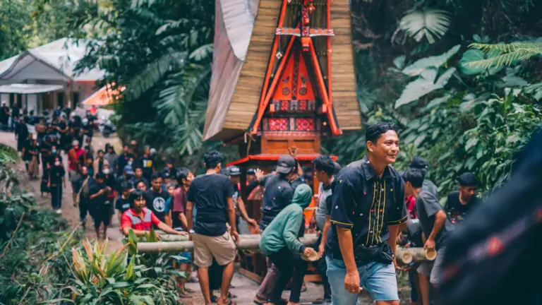 Traditionelle Zeremonie der Toraja in Tana Toraja auf Sulawesi mit Menschenmenge und kunstvoll gestaltetem Tongkonan Haus im Dschungel Indonesiens