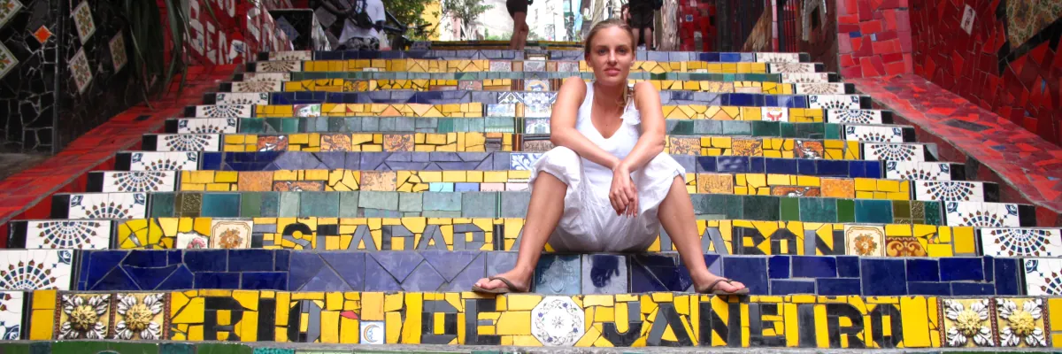 Junge Frau sitzt auf der berühmten Escadaria Selarón in Rio de Janeiro während einer Solo Reise durch Brasilien