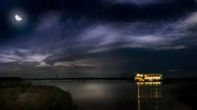 Flussschiff auf dem Amazonas bei Nacht unter Mondschein und Sternenhimmel im peruanischen Regenwald