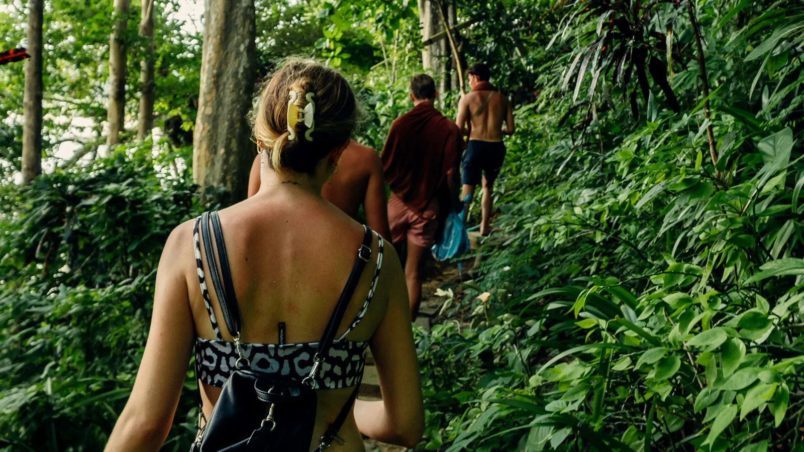 Junge Reisende wandern gemeinsam auf einem Dschungelpfad während einer Backpacking Gruppenreise
