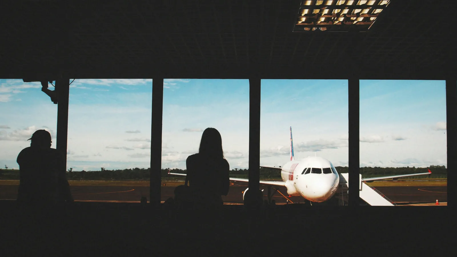 Junge Weltreisende blickt am Flughafen auf ihr Flugzeug und denkt über ihre Weltreise nach