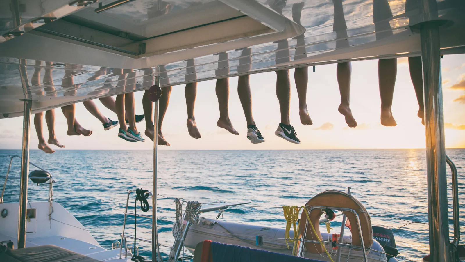 Junge Reisende genießen gemeinsam einen Sonnenuntergang auf einem Segelboot während einer internationalen Gruppenreise