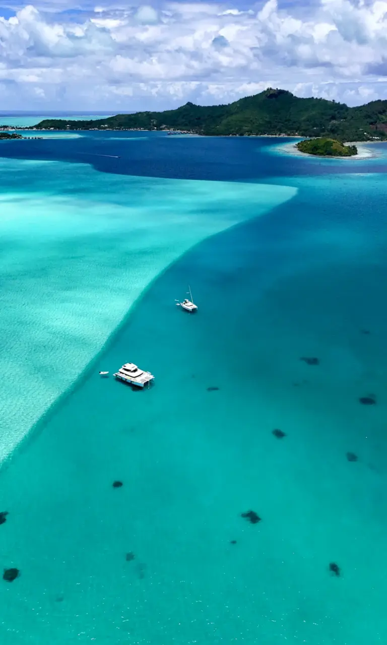 Segelkatamaran vor Anker in der türkisfarbenen Lagune von Bora Bora in Französisch-Polynesien.