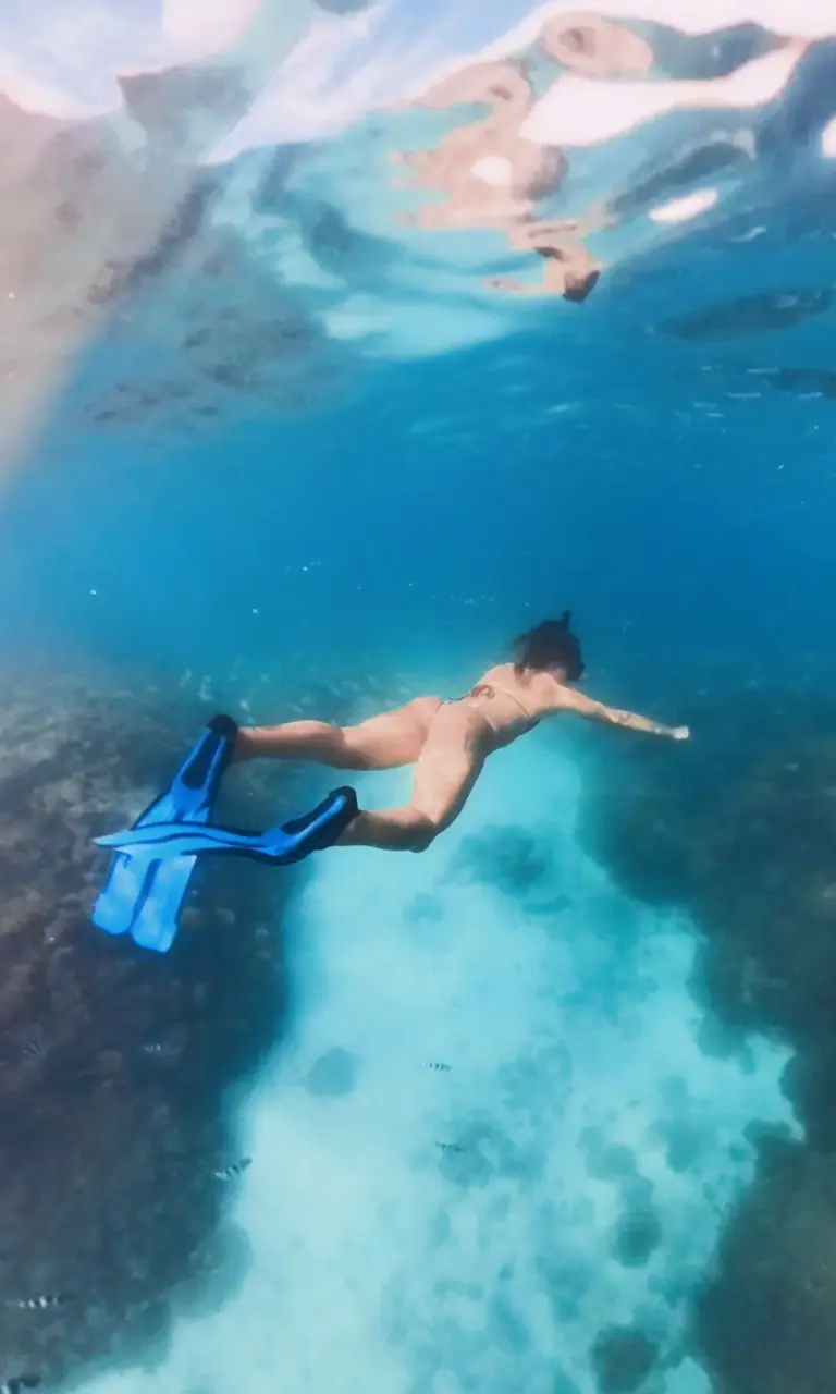 Lucia schnorchelt über einem farbenreichen Korallengarten in der türkisblauen Lagune von Französisch-Polynesien während der Functional Fitness Segelreise.