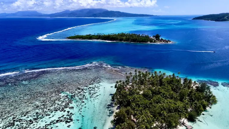 Drohnenaufnahme tropischer Inseln, Korallenriffe und türkisfarbener Lagunen in Französisch-Polynesien während einer Segelreise.