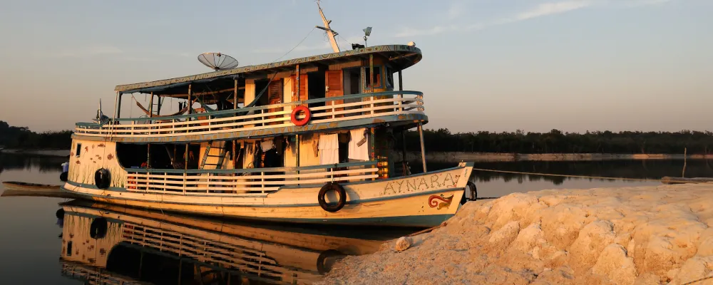 Traditionelles Amazonas Flussschiff am Flussufer bei Sonnenuntergang. Solche Schiffe sind Transportmittel und Unterkunft auf mehrwöchigen Expeditionen durch Peru, Bolivien und Brasilien