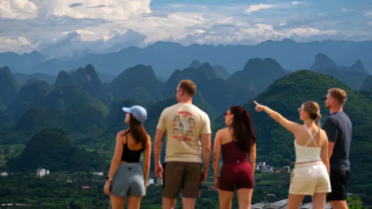 Junge Reisegruppe an einem Aussichtspunkt mit Blick auf die Karstberge von Yangshuo in China