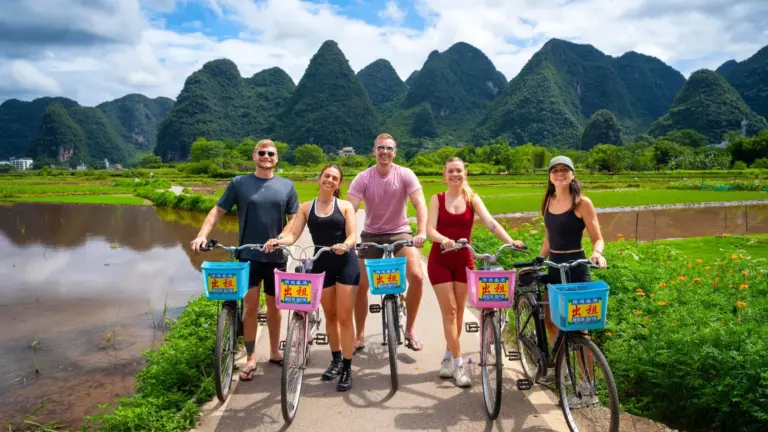 Junge Reisegruppe mit Fahrrädern vor Reisfeldern und Karstbergen bei Yangshuo in China